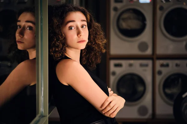 Portret pięknej dziewczyny przy oknie w nowoczesnym samoobsługowym pralni w nocy — Zdjęcie stockowe