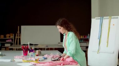 Genç ve güzel terzi modern terzi atölyesinde dokularla çalışıyor.