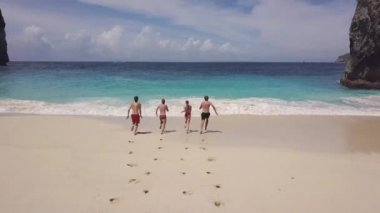 Cennet adasındaki güzel mavi okyanusta koşan gençlerin fotoğrafını çekiyorum. Tatildeki arkadaşlar