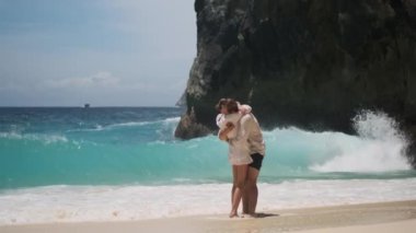 Genç romantik çift boş tropikal sahilde mavi okyanusla sarılıyor. Cennet adasında çekici bir çift. Çiftin nişanlandığı o dokunaklı an