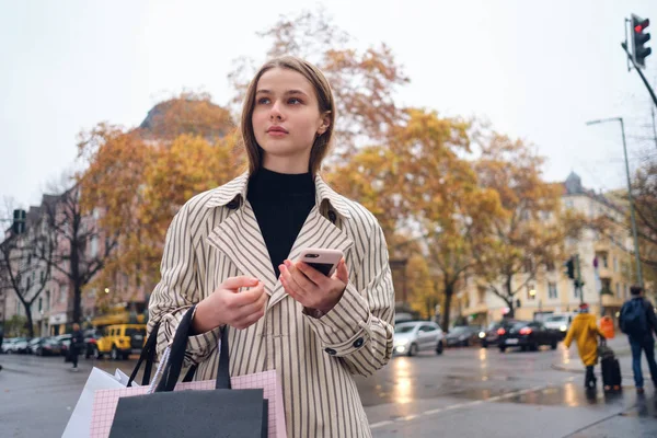아름다운 아가씨가 쇼핑백 스마트폰을 거리를 거닐고 — 스톡 사진