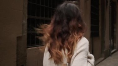 Sırt çantalı güzel bir kızın eski şehir caddesinde mutlu bir şekilde yürüdüğünü gösteren bir fotoğraf.