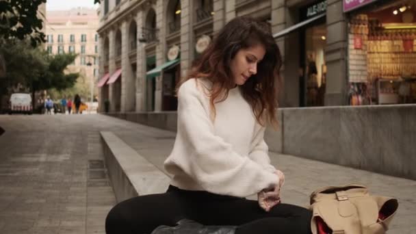美丽的惊慌失措的姑娘从背包里拿出化妆品 独自躺在舒适的城市街道上 — 图库视频影像