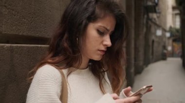İspanyol kızın Barcelona 'nın sıcacık şehir sokağında akıllı telefon kullanırken ki görüntüsü.