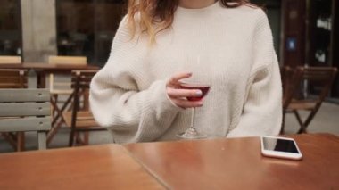 Kapalı kafeteryada elinde bir bardak şarap tutan İspanyol kazaklı kızın yakın plan fotoğrafı.