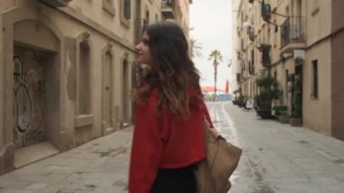Sırt çantalı, şık İspanyol bir kızın rahat bir sokakta mutlu mesut yürürken fotoğrafını çekiyorum.
