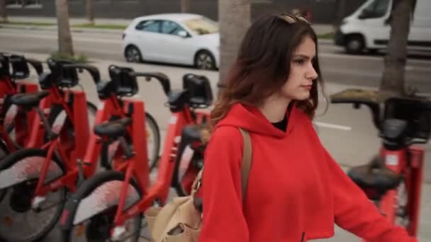 Sırt Çantalı Çekici Bir Kız Kiralık Kırmızı Bisikletle Şehir Caddesinde — Stok video