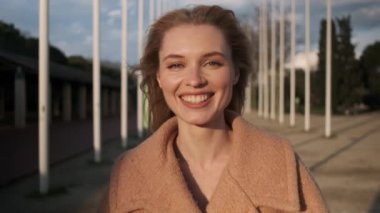 Neşeli sarışın kızın portresi kameraya bakıp gün batımında dışarıda dil gösteriyor.