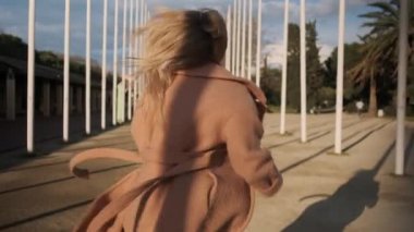 Güneş batarken parktan kaçan ceketli güzel sarışın kızın kavramsal görüntüsü.