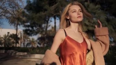 Romantik sarışın kızın gün batımında güvenli bir şekilde dışarıda yürüyüşünü çekiyorum.
