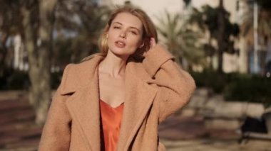 Sokakta yürürken kameraya şehvetli bir şekilde bakan muhteşem, seksi sarışın bir kız resmi.