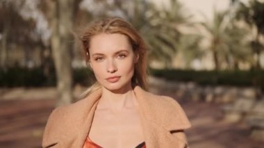 Güzel, romantik, sarışın kız kameraya bakıyor. Sokakta tek başına yürüyor. 