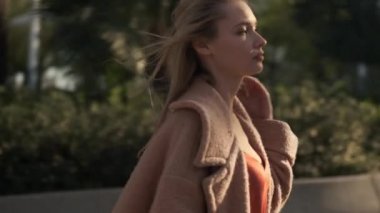 Romantik sarışın kızın şehir parkında güvenle yürürken görüntüsü.