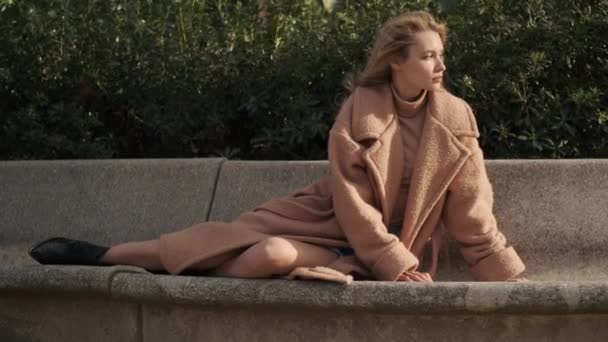 在拍摄迷人的金发姑娘的镜头时 她若有所思地回头望着城市公园的长椅 — 图库视频影像
