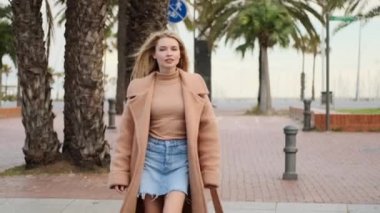 Çekici, şık, sarışın kızın görüntüsü rahat caddede güvenli bir şekilde karşıdan karşıya geçiyor.