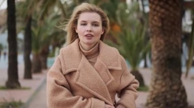 Rüzgarlı caddede yürürken ceketini bağlayan şık sarışın kızın fotoğrafını çekiyorum.