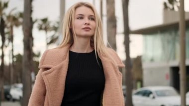 Çekici, şık, sarışın bir kızın portresi. Şehir caddesinde rahatça yürüyor.