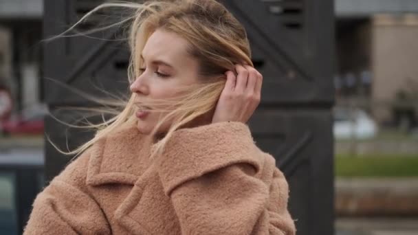 Tracking Shot Beautiful Blond Girl Coat Holding Hair Wind Dreamily — Stock Video