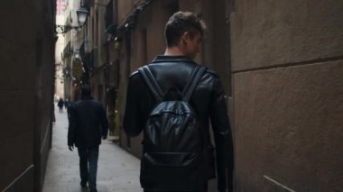 Sırt çantalı çekici bir genç Barcelona 'da dar şehir caddesinde yürüyor.