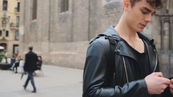 Улице Барселоны Молодой Человек Кожаной Куртке Помощью Смартфона Разгуливает Городу — стоковое видео