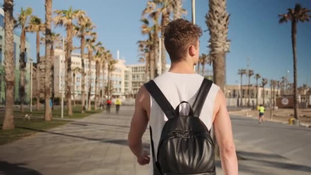 Visão Traseira Tiro Jovem Fit Guy Com Mochila Andando Longo — Vídeo de Stock