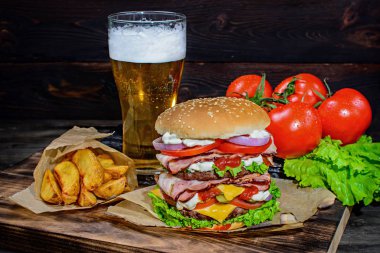 Büyük hamburger ve ahşap bir masa üzerinde hafif bira