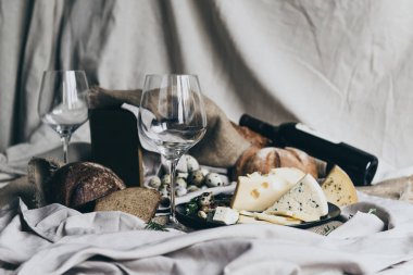 İki boş kadehlerin arkasında yatan kuru kırmızı şarap ile doldurulması için hazır duruyor. Taze ekmek, mavi peynir, masdaam peynir ve Bıldırcın yumurta dekorasyon olarak kullanılır.