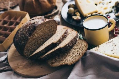Yaprakları sarı bir şık bardak süt ve peynir delikleri ve fındık ile siyah bir fincan ile bej renkli arka plan üzerinde yalan ekmek. Kahvaltı veya brunch için mükemmel sağlıklı gıda sevenler için.