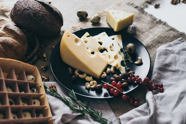 Üstten Görünüm siyah bir yemek ve bir yumurta kutusu. Bu yemek lezzetli snacks: otlar, çilek ve fındık ile pahalı peynir. Sarı, bej ve kahverengi renklerde organik gıda