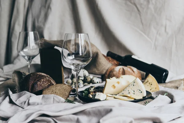 İki boş kadehlerin arkasında yatan kuru kırmızı şarap ile doldurulması için hazır duruyor. Taze ekmek, mavi peynir, masdaam peynir ve Bıldırcın yumurta dekorasyon olarak kullanılır.