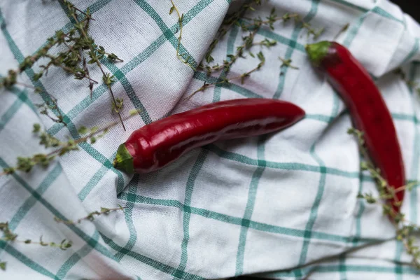 İki kırmızı sıcak biber bol dökümlü bir kumaş üzerine yalan söylüyorsun. Hurbs dekorasyon olarak kullanılır.