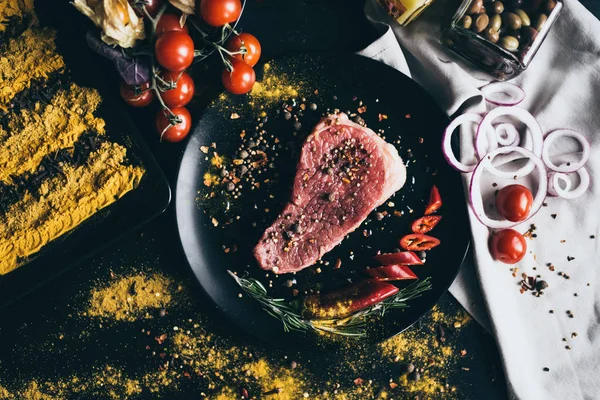 Çiğ et baharatlar, cherry domates, biber, soğan ve zeytin, siyah arkaplan ve beyaz peçete üzerinde yalan ile. Parti için lezzetli akşam yemeği veya romantik bir akşam için iki aşık pişirme.