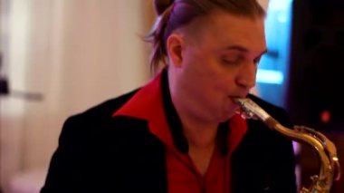 Kırmızı gömlek ve uzun saç saksofoncu çalış.