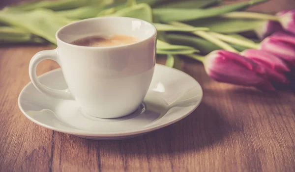 Coffee cup with tulips on wooden back ground — Stock Photo, Image