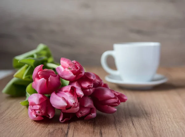 Coffee cup with tulips on wooden back ground — Stock Photo, Image