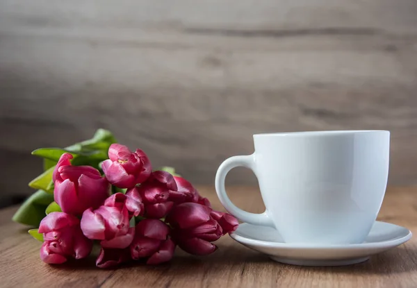 coffee cup with tulips on wooden back ground