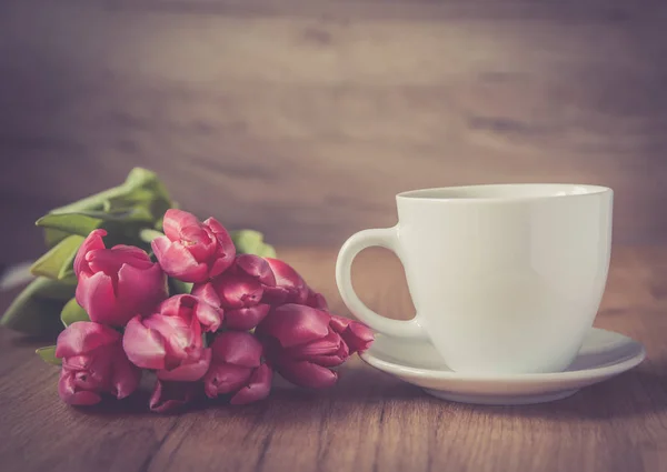 coffee cup with tulips on wooden back ground