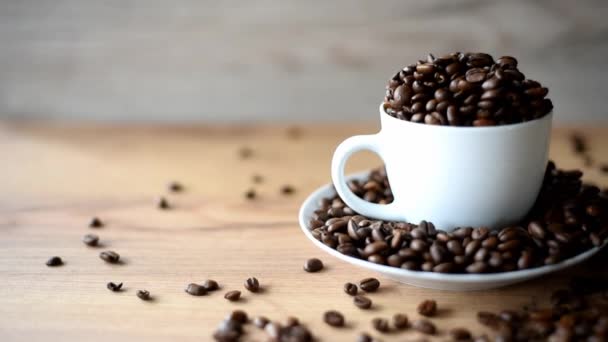 Coffee cup filled by coffee beans on wooden background — Stock Video