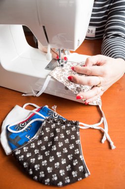 Ev yapımı nefes maskesi yapan genç bir kadın, Corona virüsü koruması. Öksürüğü, tozu, kirliliği, COVID-19 'u ve diğer kirliliği koruyun. Virüs maskesi dikiyorum, ev yapımı.