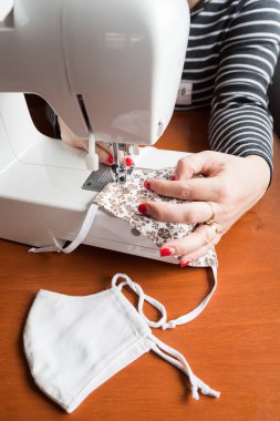 Ev yapımı nefes maskesi yapan genç bir kadın, Corona virüsü koruması. Öksürüğü, tozu, kirliliği, COVID-19 'u ve diğer kirliliği koruyun. Virüs maskesi dikiyorum, ev yapımı.