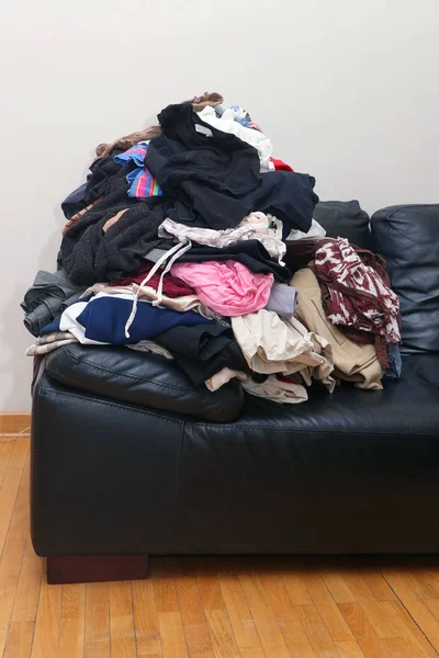 Pila de ropa desordenada en sofá de cuero — Foto de Stock