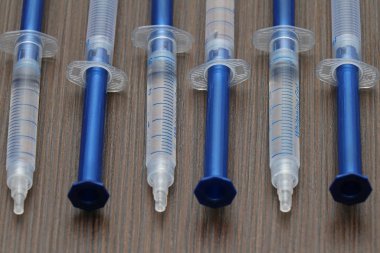 Tahta masada diş beyazlatma jeliyle dolu plastik şırıngalar.