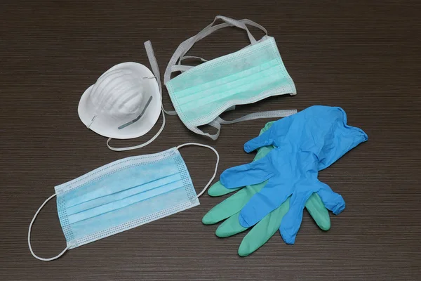 Protective surgical face mask and rubber gloves on wooden table