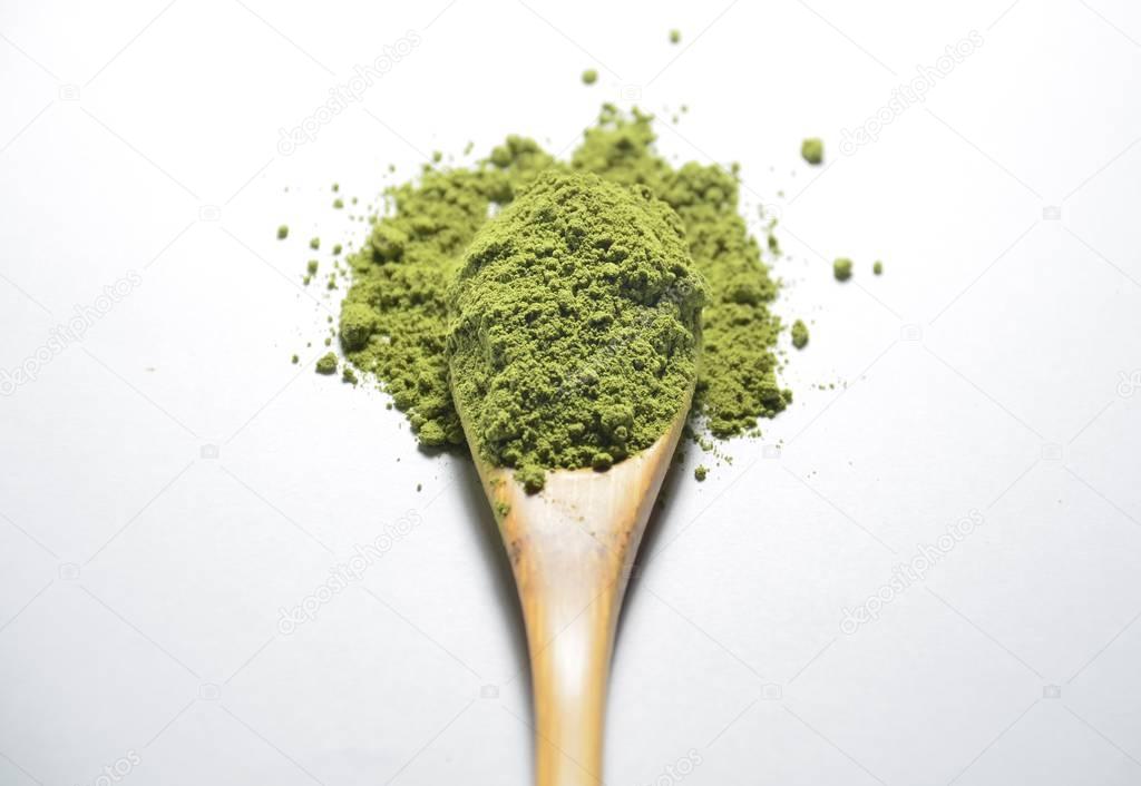 Matcha green tea powder in wooden spoon isolated on white background