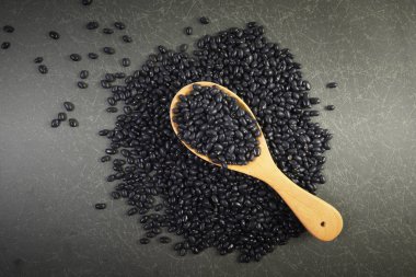 Tohumlar siyah fasulye gri arka plan üzerinde tahta kaşık sağlık için yararlı.