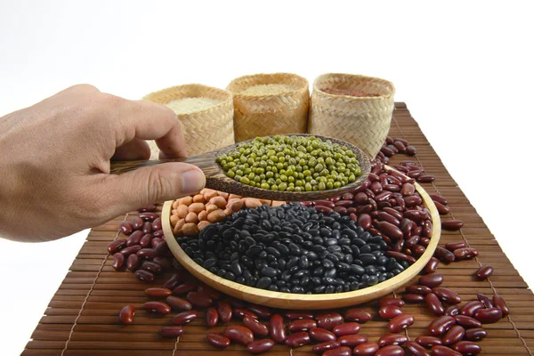 Granos de cereales y semillas (frijol negro, frijol rojo, cacahuete, frijol mungo, arroz jazmín tailandés, arroz integral y arroz blanco) útiles para la salud en cucharas de madera sobre fondo blanco . —  Fotos de Stock