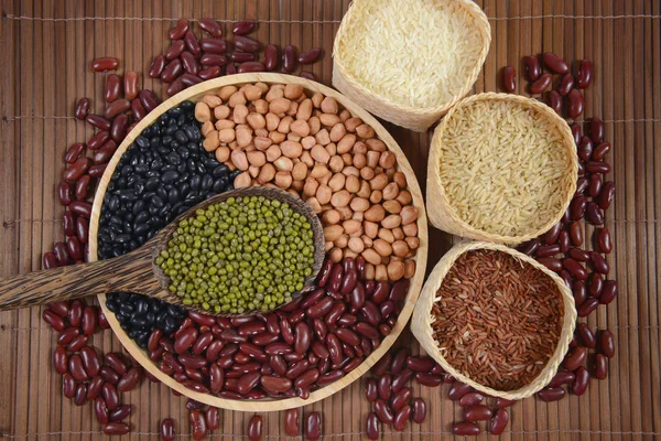 Cereal grains and Seeds beans(Black Bean, Red Bean, Peanut, Mung Bean, Thai Jasmine Rice, Brown Rice and White Rice) useful for health in wood spoons on wood background.