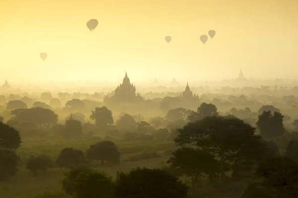 Horkovzdušné balóny létat nad bojištěm starobylé město pagody na siluetu sunrise scéně v Bagan, Myanmar. — Stock fotografie