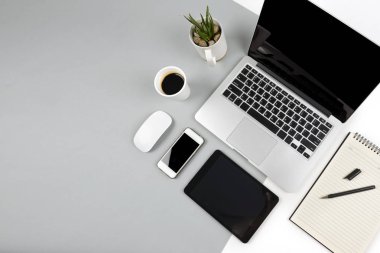 Dizüstü bilgisayar, dizüstü bilgisayar, dijital tablet ve modern iki ton (beyaz ve gri) arka plan üstünde smartphone ile ofis masaları.