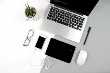 Dizüstü bilgisayar, dijital tablet ve modern iki ton (beyaz ve gri) arka plan üstünde hareket eden telefon ile ofis masaları.